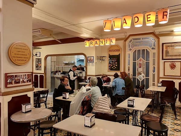 Clientes disfrutando chocolate con churros en Granja Viader