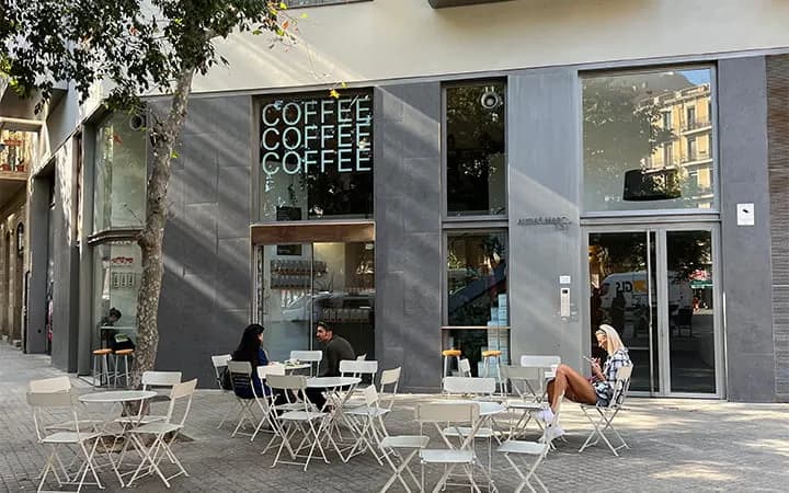 Exterior de Three Marks Coffee en el barrio de Gràcia, con mesas al aire libre