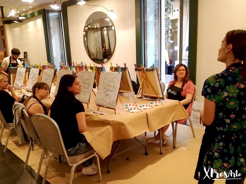 Pareja pintando cuadros en Xpresarte Madrid con copas de vino